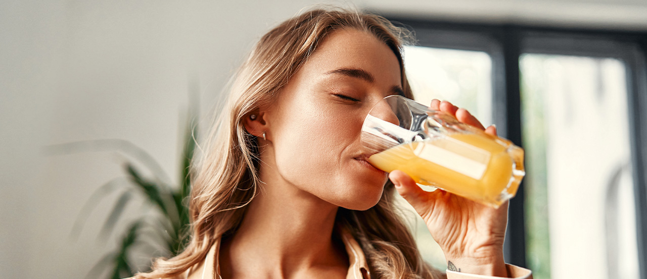 Mujer sana bebiendo jugo de naranja para obtener vitamina C